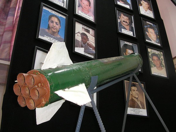 A Qassam Rocket Displayed in Sderot Town Hall A_Qassam_rocket_is_displayed_in_Sderot_town_hall_against_a_background_of_pictures_of_residents_killed_in_rocket_attacks