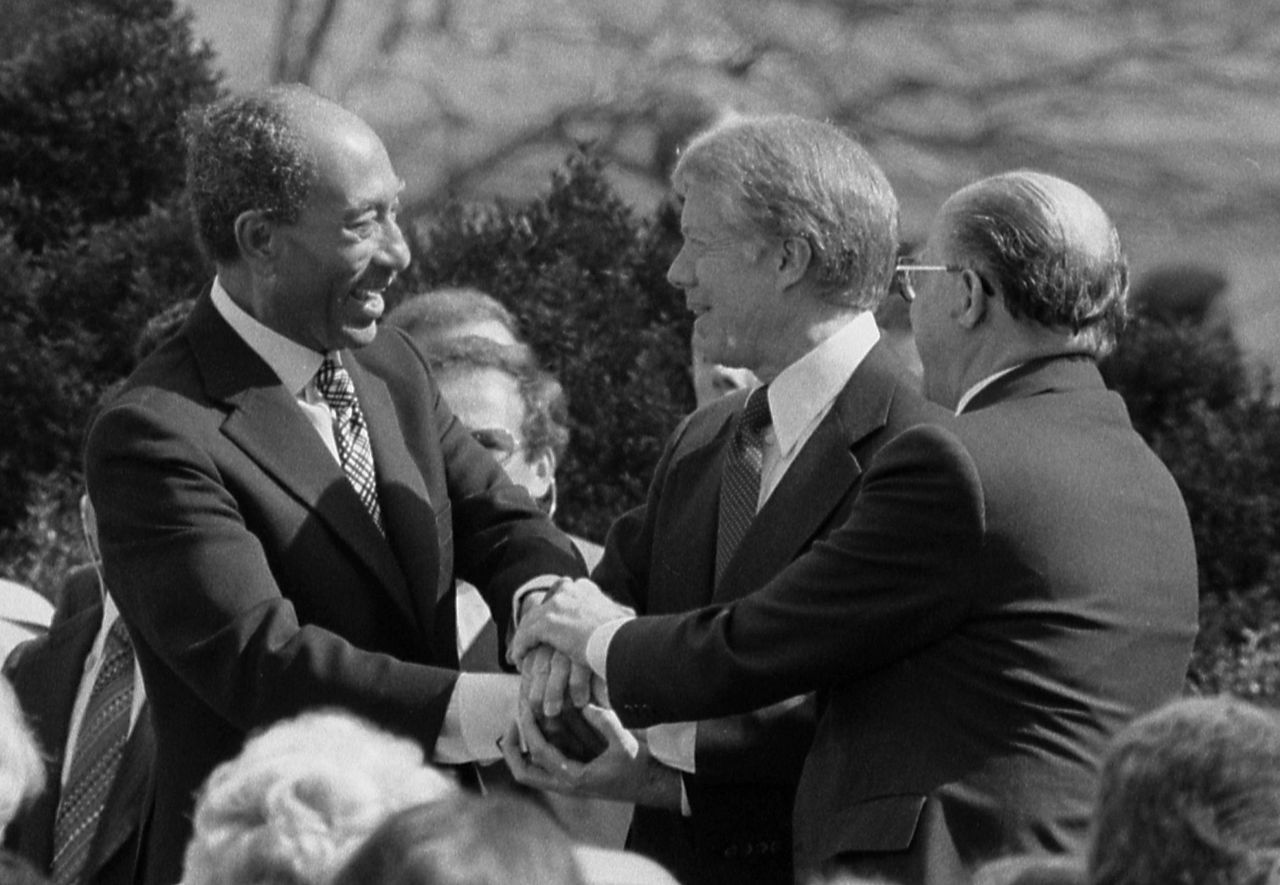 President Jimmy Carter shakes hands with Egyptian President Anwar Sadat and Israeli Prime Minister Menachem Begin at the signing of the Egyptian-Israeli Peace Treaty on the grounds of the White House.