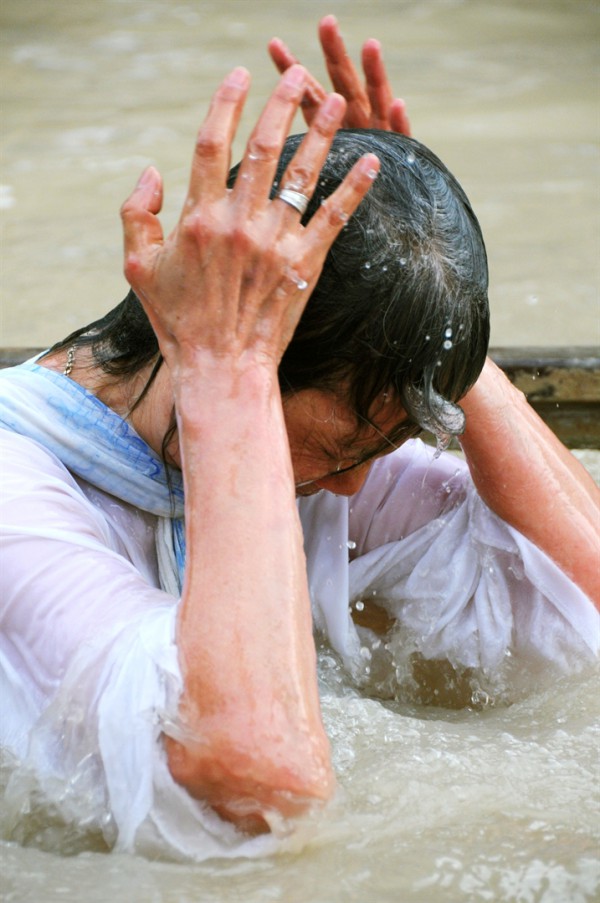 A Christian pilgrim wearing a robe dips into the banks of the Jordan River at Qasr el Yahud. A Christian pilgrim wearing a robe dips into the banks of the Jordan River at Qasr el Yahud.