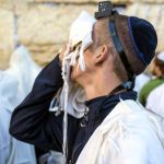 A Jewish man wearing tefillin (phylacteries) recites selichot (prayer for forgiveness and mercy) at the Western (Wailing) Wall during the Days of Awe.