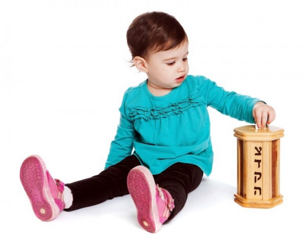 Toddler puts charity in the tzedakah (pushke) box