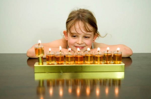 A girl admires a fully lit Chanukah menorah