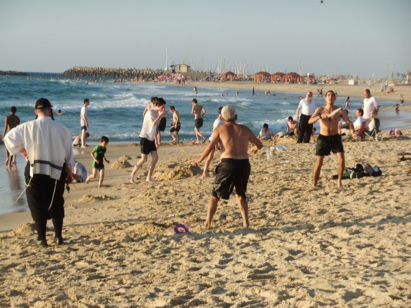 An ultra-Orthodox man remains fully dressed on a beach in Israel.