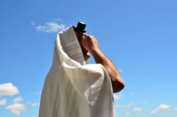 A Jewish man prays wearing a tallit (prayer shawl) and tefillin (phylacteries).