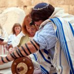 A woman reads from the Torah scroll in Jerusalem near the Western (Wailing) Wall. (Photo by Josh Evnin)