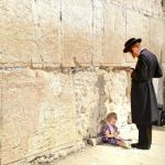 A child sits at her father's feet as he prays at the Western (Wailing) Wall in Jerusalem. (Israel Tourism photo by VuTheara Kham)