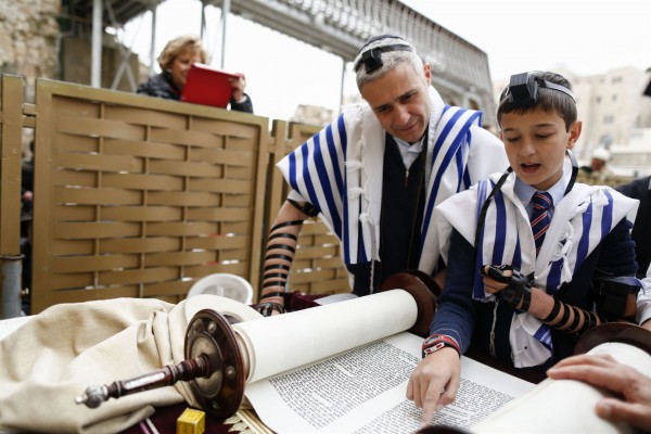 A 13-year-old Jewish boy wearing tefillin (phylacteries) and a tallit (prayer shawl) reads from the Torah at the Western (Wailing) Wall. (Israel Ministry of Tourism photo by Yonatan Sindel, Flash 90)