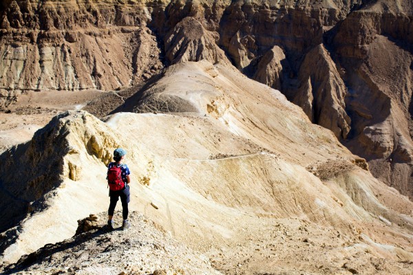 A woman stands on a mountain peak in Israel's desert.