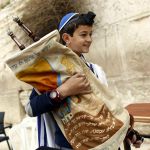 A 13-year-old Jewish boy carries the Torah scroll at the Western (Wailing) Wall. (Israel Ministry of Tourism photo by Jonathan Sindel)