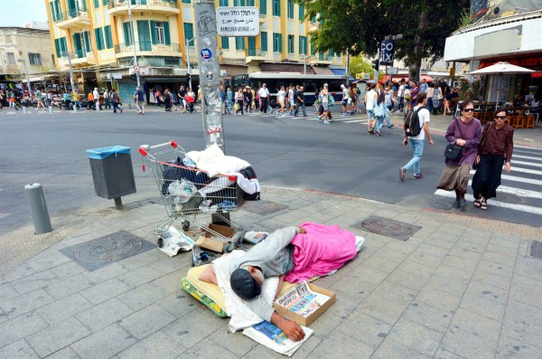 A homeless man sleeps on a street corner in Tel Aviv.