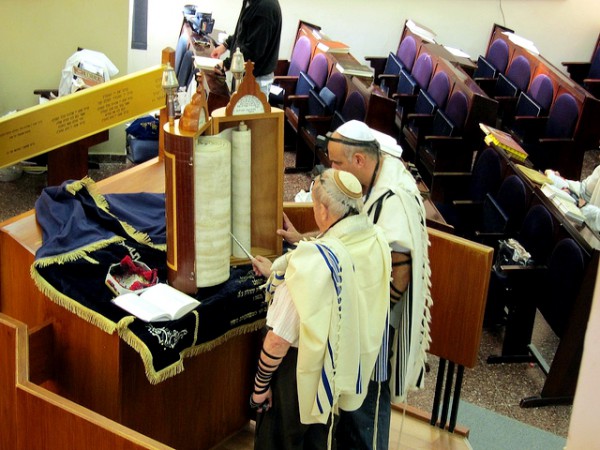 Reading from a Torah scroll encased in a protective Torah tik (case).