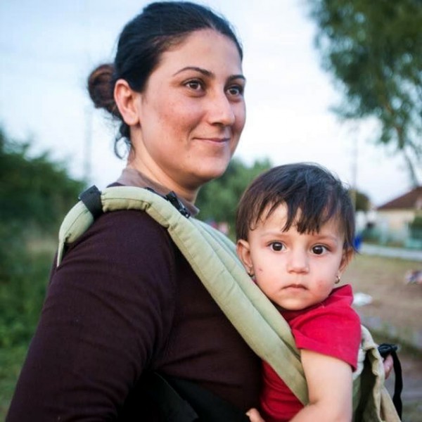 A refugee happily receives from IsraAID a baby sling that will make the flight to safety a little easier.  (Photo: IsraAID Facebook)