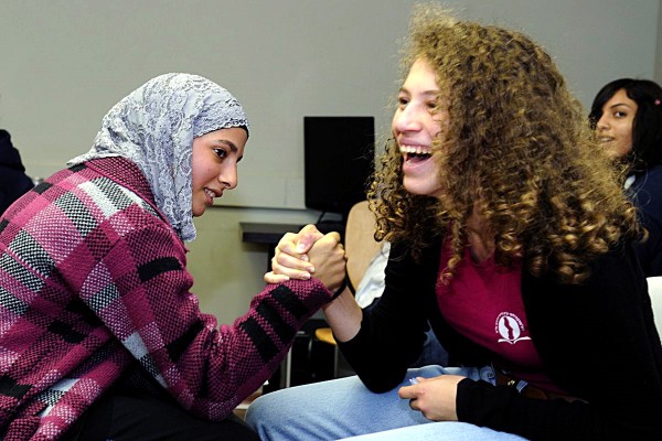 Arab and Jewish students playfully arm wrestle together. (US Embassy Tel Aviv)