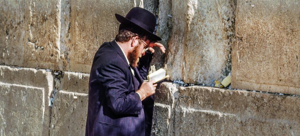 Jewish man reads from a siddur (Jewish prayer book) at the western (Wailing) Wall.