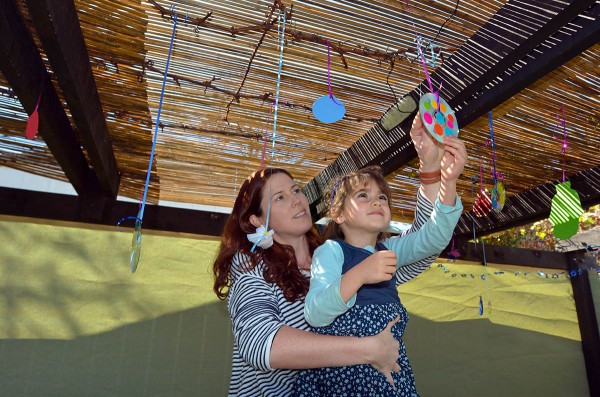 Jewish mother and daughter decorate their sukkah