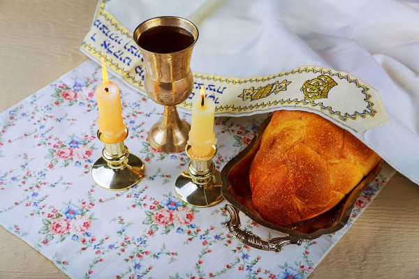 Traditional Jewish symbols of Shabbat: candles, challah bread, wine, and tallit (prayer shawl)