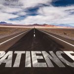 The word "patience" is written on a road that goes through the desert.